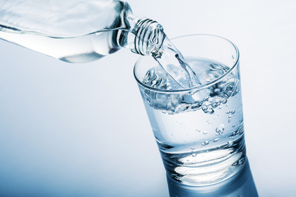 Wasserflasche füllt Glas mit Wasser